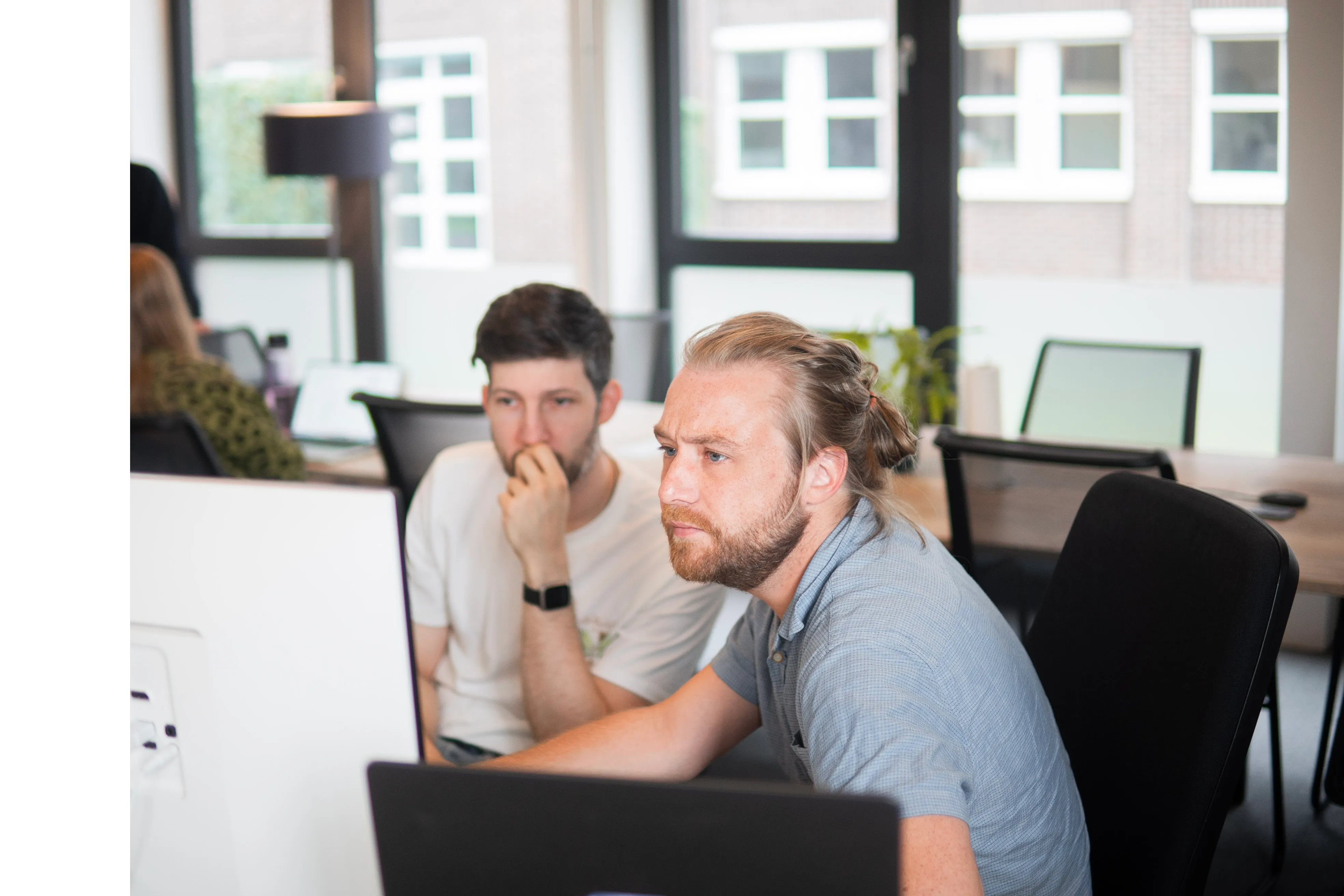 Zwei Entwickler blicken konzentriert auf einen Bildschirm im Büro